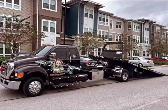 Yayi’s Towing flatbed loading a car outside apartments in Polk County, FL