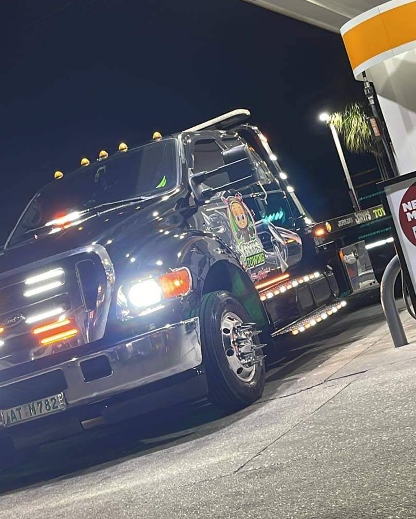 Yayi’s Towing flatbed tow truck lit up at night in Polk County, Florida